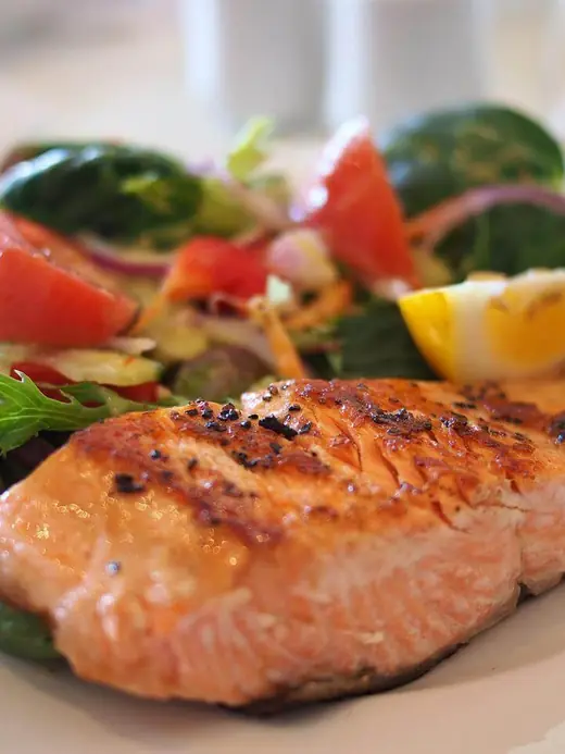 Gebratenes Lachsfilet mit Salat und Zitrone